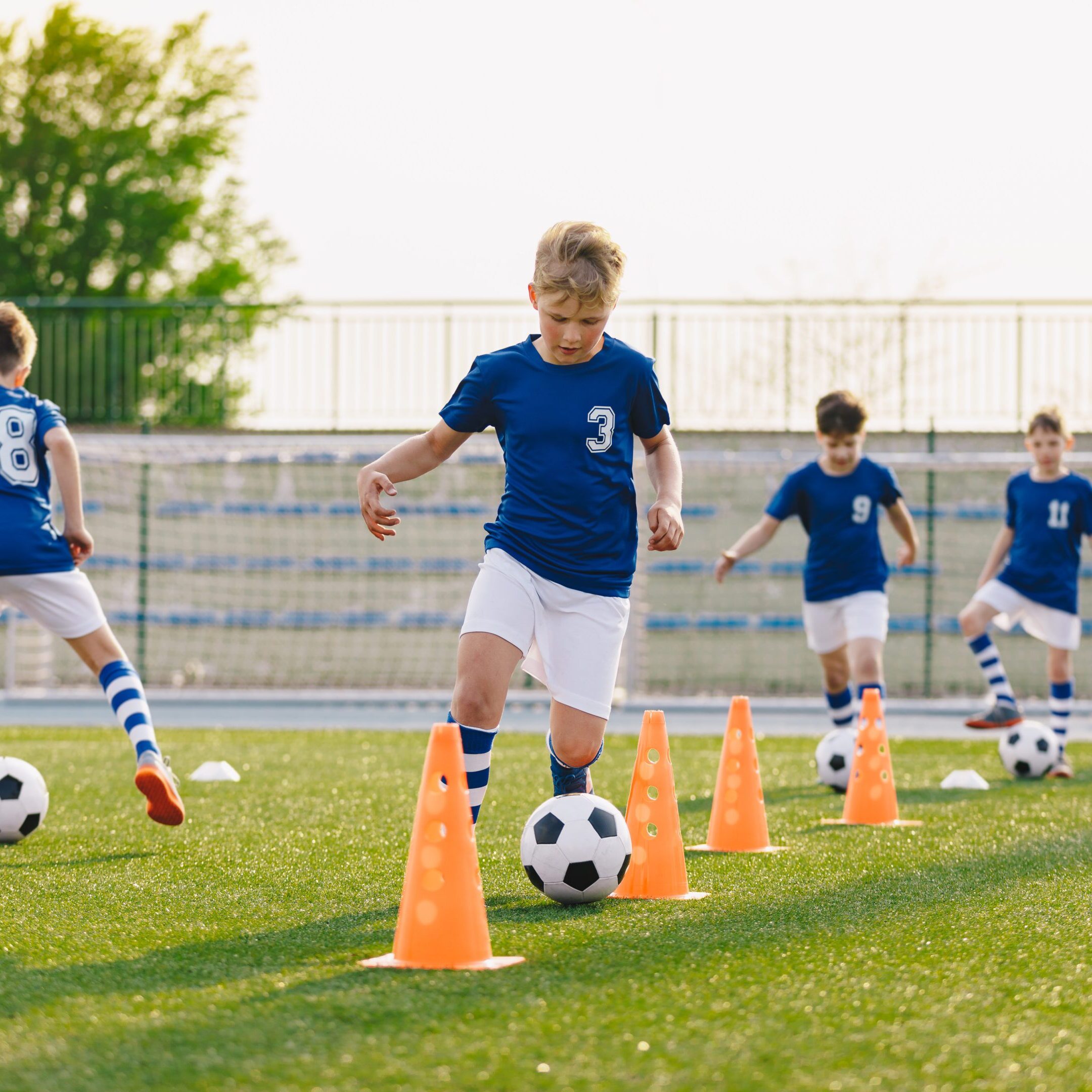 Soccer Training - Warm Up and Slalom Drills. Boys Practicing European Soccer on the Grass School Field